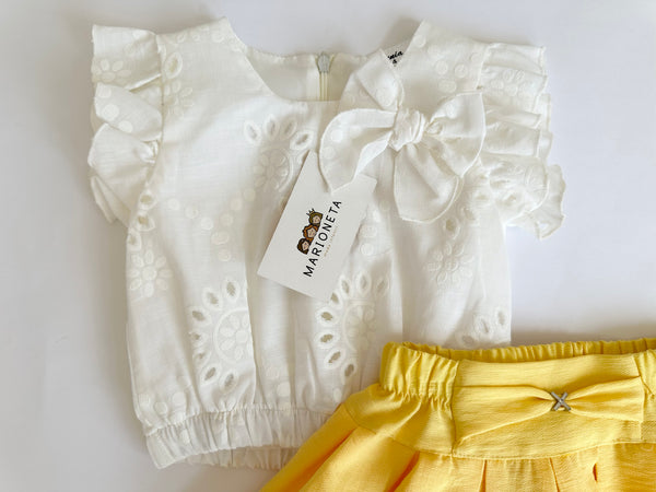 Conjunto dos piezas blusa blanca con detalle de moño y falda con olan color amarillo para niña.