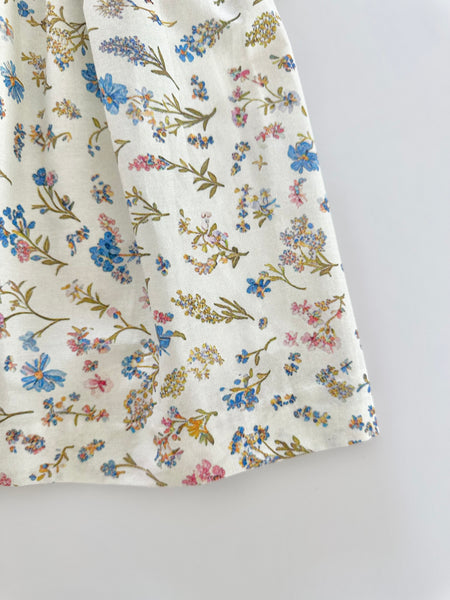 Vestido bordado hecho a mano color beige con estampado de flores azules para niña.