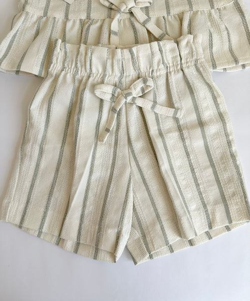 Conjunto dos piezas blusa con detalle de moños al frente y short beige con rayas verdes para niña.