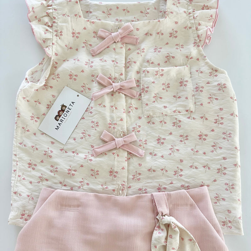 Conjunto dos piezas blusa ivory con detalle de moños al frente y falda short color rosa para niña.