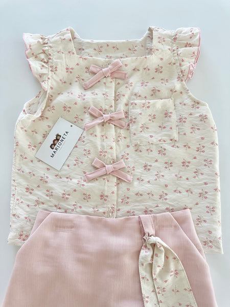 Conjunto dos piezas blusa ivory con detalle de moños al frente y falda short color rosa para niña.