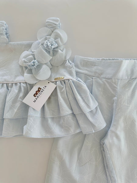 Conjunto dos piezas blusa con adorno de flores y pantlon azul para niña.