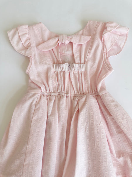 Vestido con detalle de botones y olanes color rosita para niña.