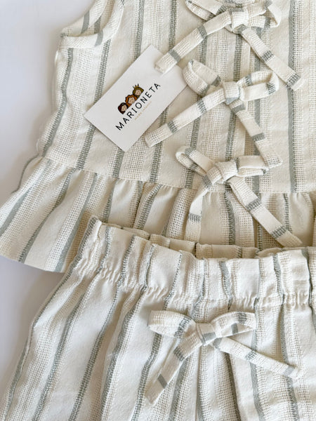 Conjunto dos piezas blusa con detalle de moños al frente y short beige con rayas verdes para niña.