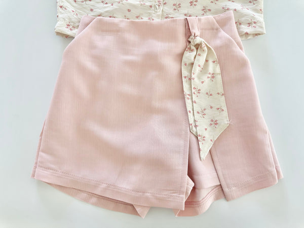 Conjunto dos piezas blusa ivory con detalle de moños al frente y falda short color rosa para niña.