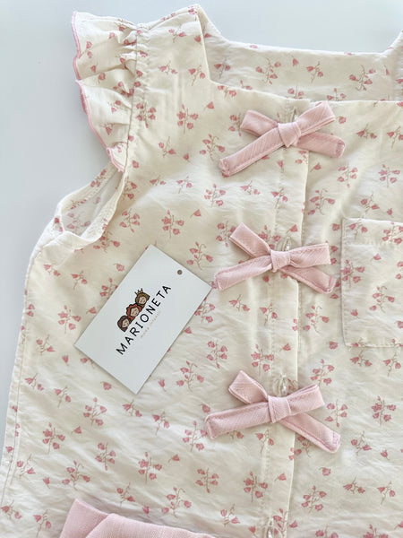 Conjunto dos piezas blusa ivory con detalle de moños al frente y falda short color rosa para niña.