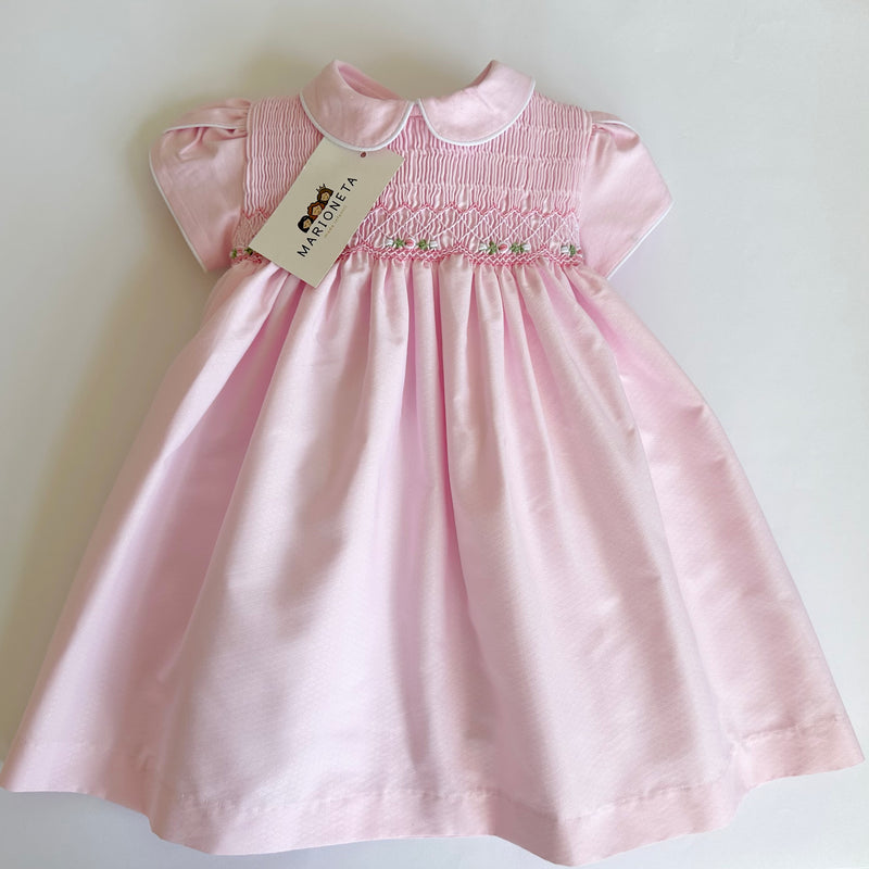 Vestido bordado hecho a mano color rosa con bordado blanco con verde y borde blanco terminado en cuello y mangas para niña.