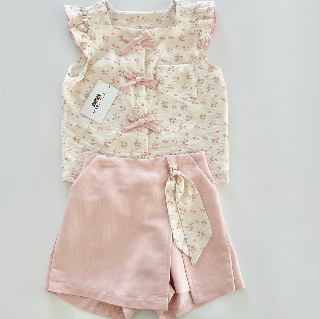 Conjunto dos piezas blusa ivory con detalle de moños al frente y falda short color rosa para niña.