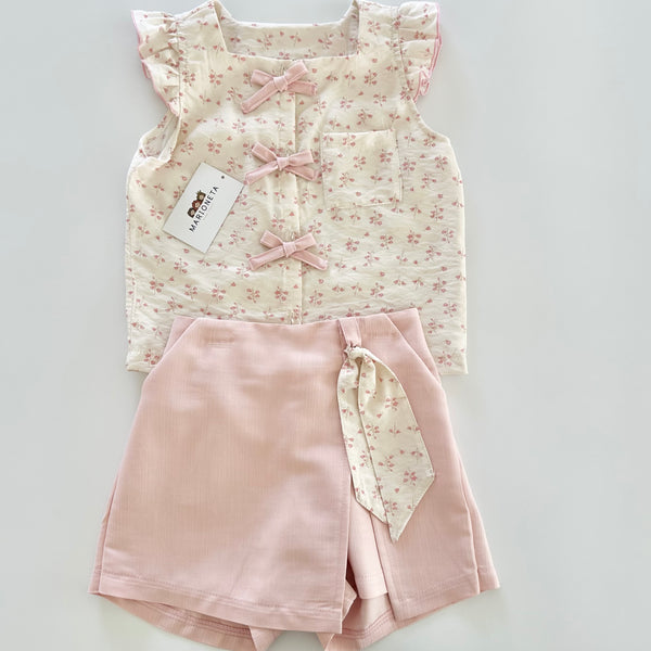 Conjunto dos piezas blusa ivory con detalle de moños al frente y falda short color rosa para niña.