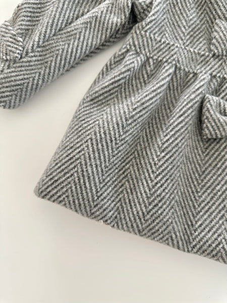 Abrigo color gris con adorno de lazos al frente para niña .|