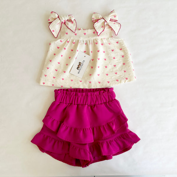 Conjunto dos piezas blusa ivory con estampado de corazones y lazos al frente y falda short fiucha para niña .