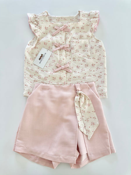Conjunto dos piezas blusa ivory con detalle de moños al frente y falda short color rosa para niña.