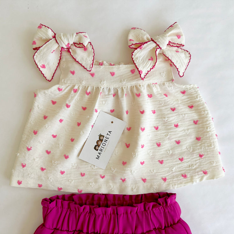 Conjunto dos piezas blusa ivory con estampado de corazones y lazos al frente y falda short fiucha para niña .