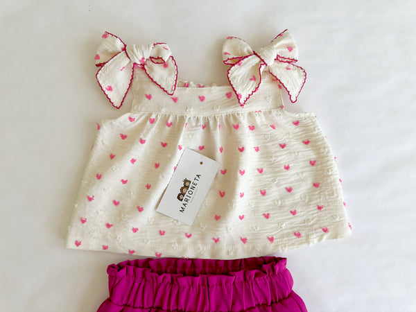 Conjunto dos piezas blusa ivory con estampado de corazones y lazos al frente y falda short fiucha para niña .