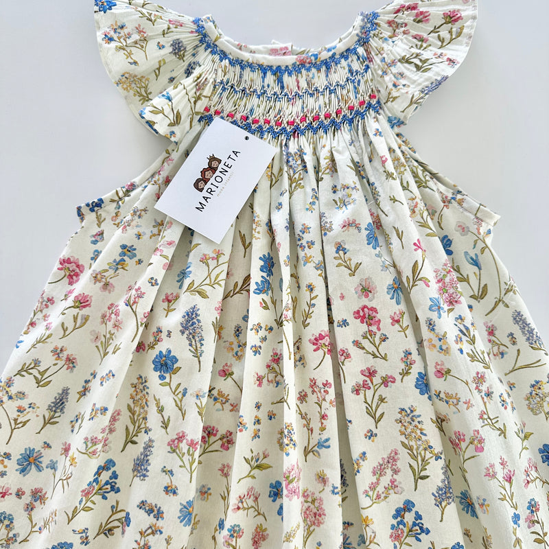 Vestido jesucito bordado hecho a mano color ivory con estampado bordado de flores azules para niña.